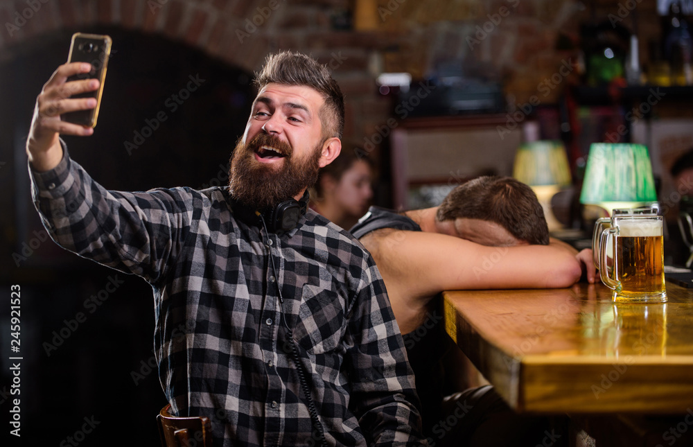 Taking selfie concept. Online communication. Send selfie to friends social networks. Man in bar drinking beer. Take selfie photo to remember great evening in pub. Man bearded hipster hold smartphone