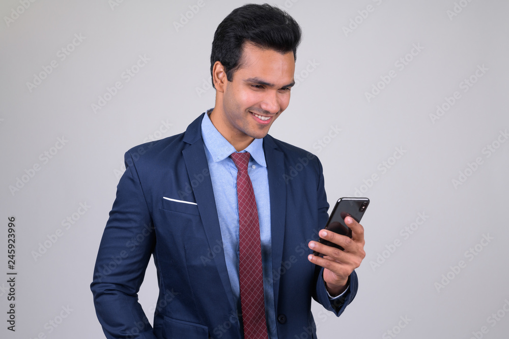 Happy young handsome Indian businessman using phone Happy young handsome Indian businessman using phone