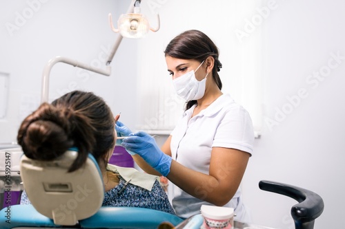 Dentist girl treats the patient s teeth on the dental chair with tools