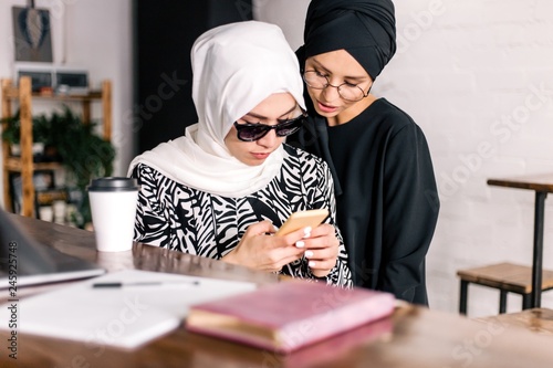 Two girls break the password on the phone sitting in a cafe