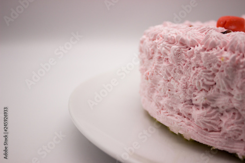 The piece of a cream pink cake on a plate on a white-gray background. Image with a copy space area.