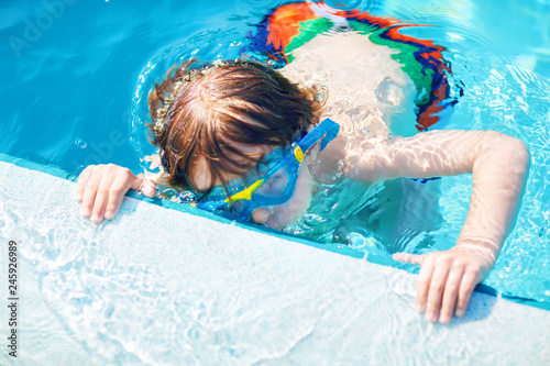 little preschool kid boy making swim competition sport. Kid with swimming goggles reaching edge of the pool . Child having fun in an swimming pool. Active happy child winning. sports, active leisure.