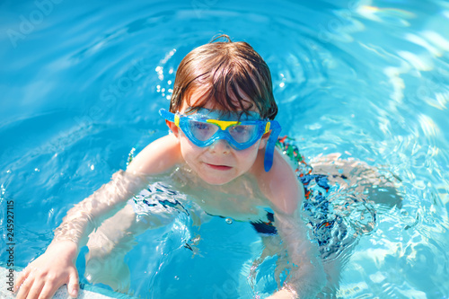 little preschool kid boy making swim competition sport. Kid with swimming goggles reaching edge of the pool . Child having fun in an swimming pool. Active happy child winning. sports, active leisure. © Irina Schmidt