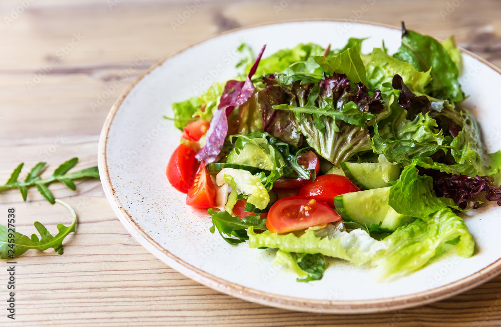 Bowl of salad with vegetables on wooden table. Bowl of salad with vegetables on wooden table.