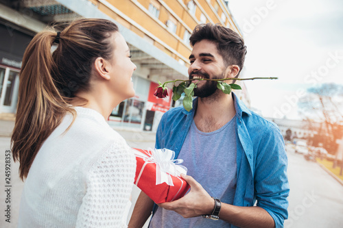 Romantic man giving flower and gift box to woman for Valentines day