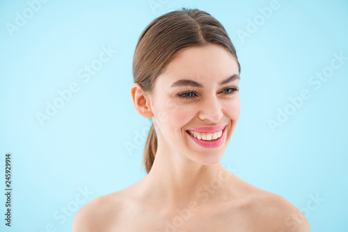 Happy cheerful beautiful young woman posing isolated over blue background.