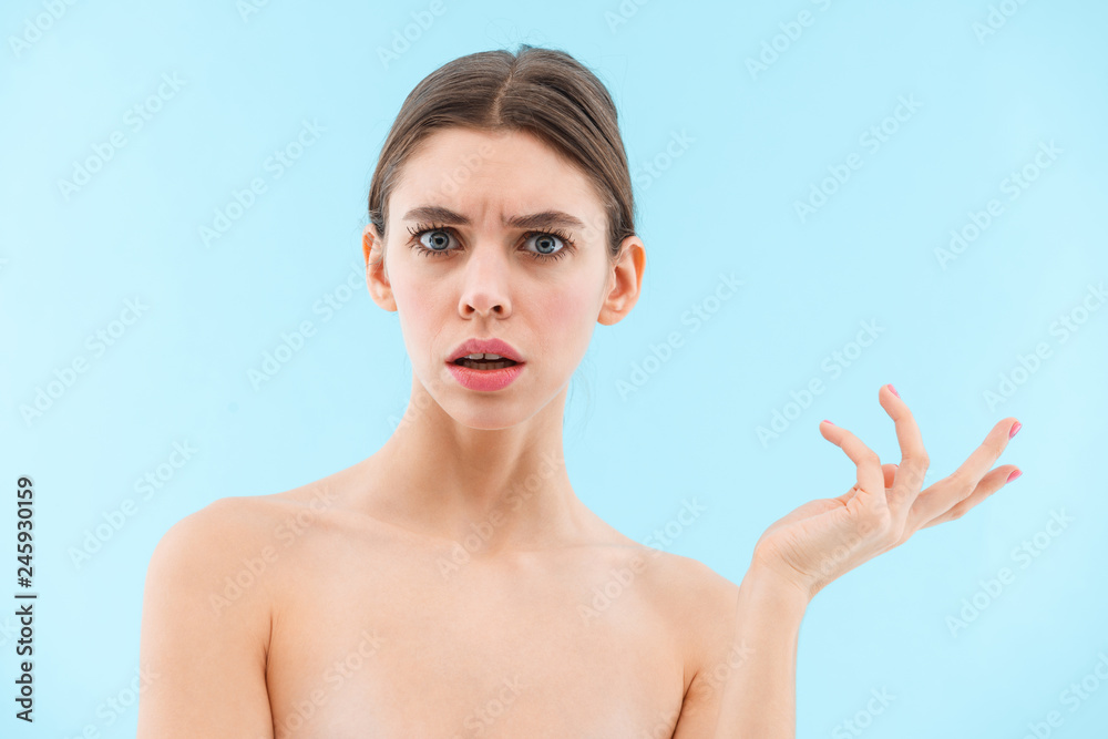 Beautiful confused young woman posing isolated over blue background. Beautiful confused young woman posing isolated over blue background.