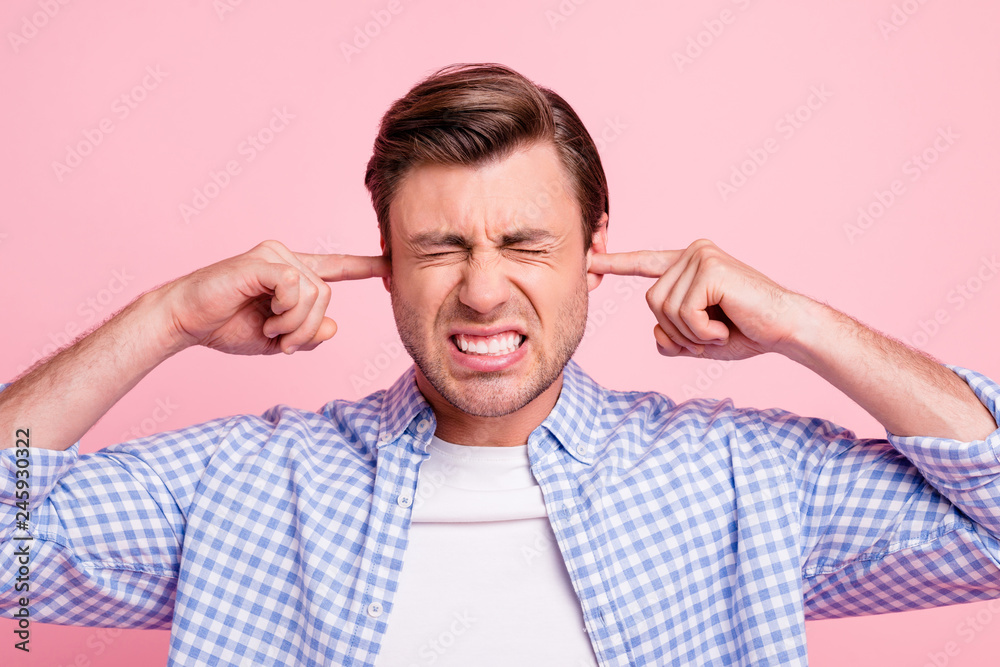 Close up photo of attractive but struggling he him his man fingers in ears eyes teeth closed tight wearing casual shirt outfit isolated on pale rose background Close up photo of attractive but struggling he him his man fingers in ears eyes teeth closed tight wearing casual shirt outfit isolated on pale rose background