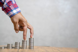 Hand with fingers man putting on coin and looking for saving money, collect money with earning bank deposit interest and take time. Business ideas concept with gray background - Image
