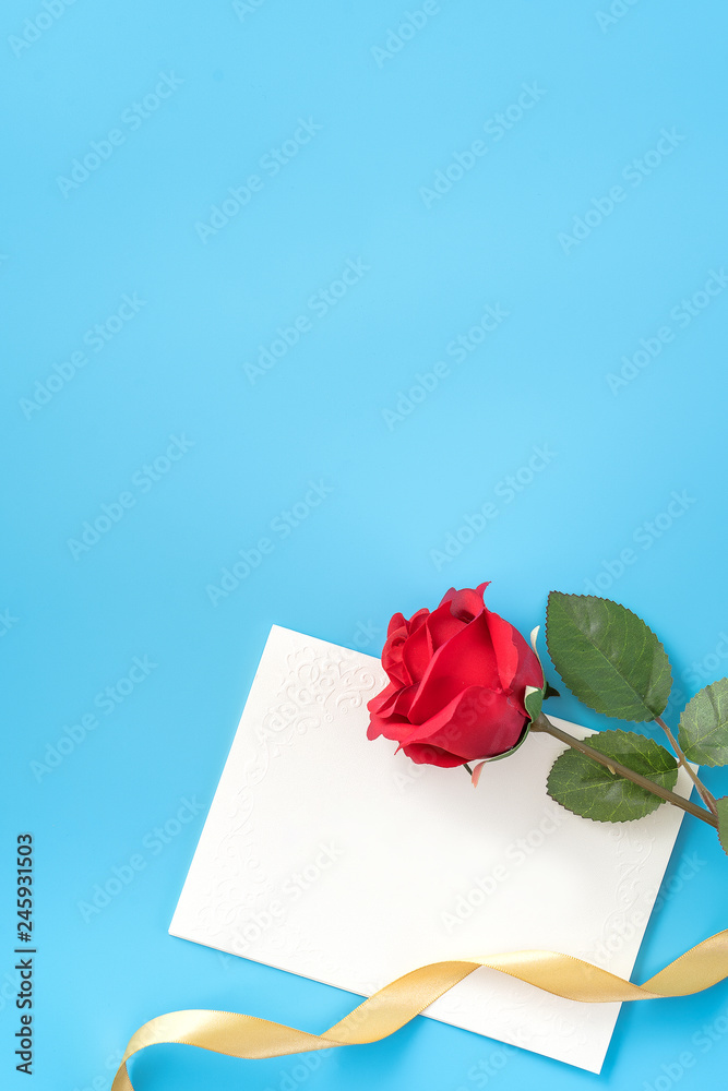Fototapeta premium Beautiful greeting card with golden ribbon for Valentine's day, anniversary, mother's day and birthday on blue background, copyspace, topview, mockup, flatlay