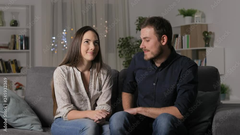 Man rejecting a girl in a first date on a couch in the night at home Man rejecting a girl in a first date on a couch in the night at home