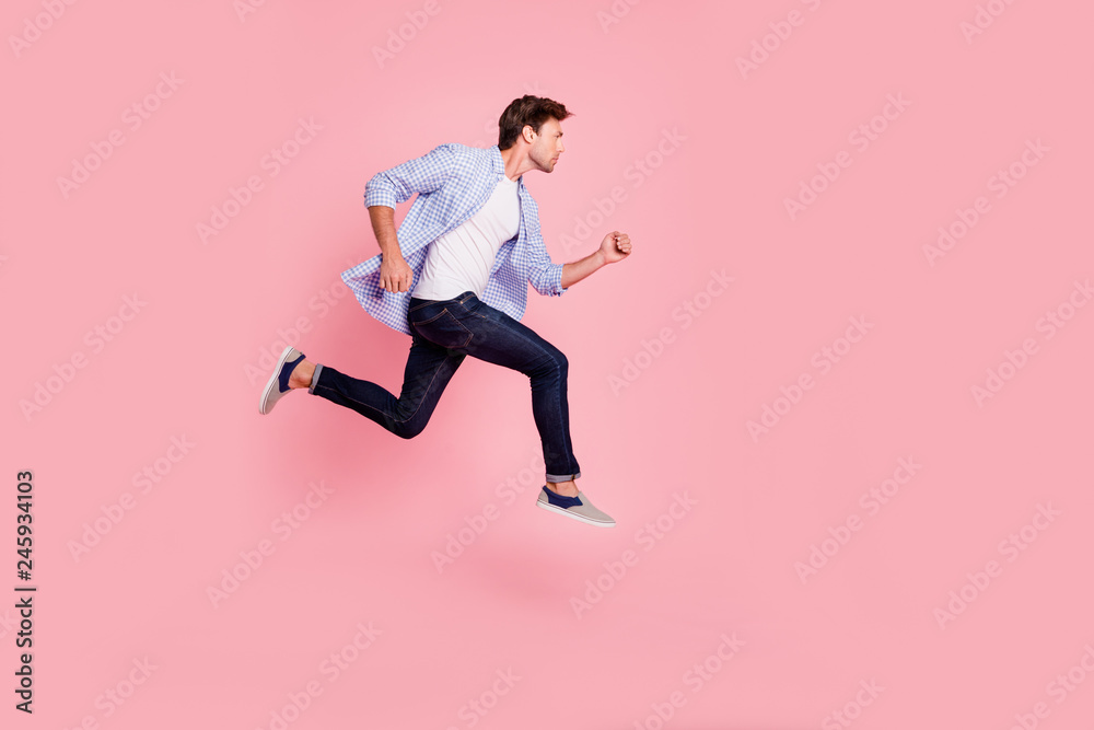 Full length side profile body size photo of jumping high he his him handsome run fast  look empty space need win victory winner wearing casual jeans checkered plaid shirt isolated on rose background