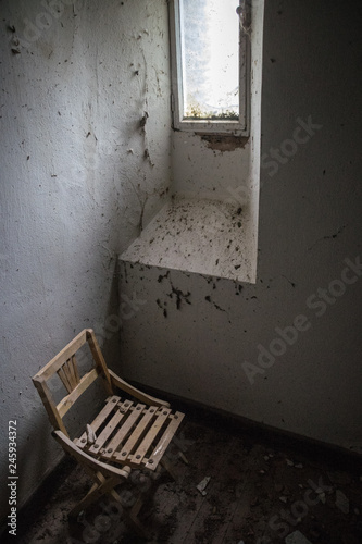 verlassenes alter Burgzimmer mit altem zerbrechlichem Stuhl vor einem Rundbogenfester © ramonmaesfotografie
