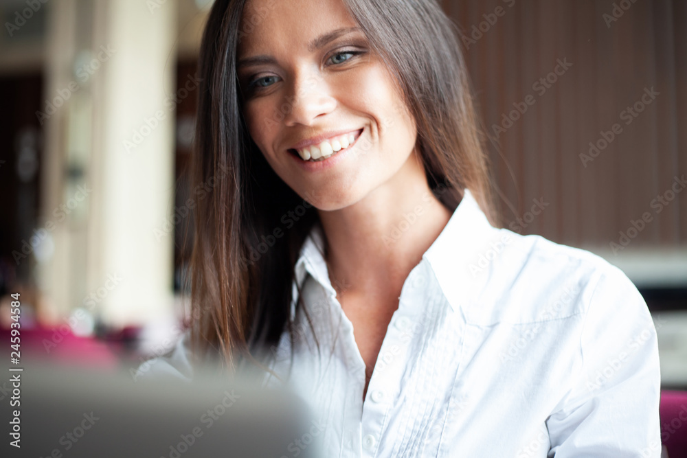 Young smiling businesswoman on a break in a cafe. She is working at laptop and drinking coffee Young smiling businesswoman on a break in a cafe. She is working at laptop and drinking coffee
