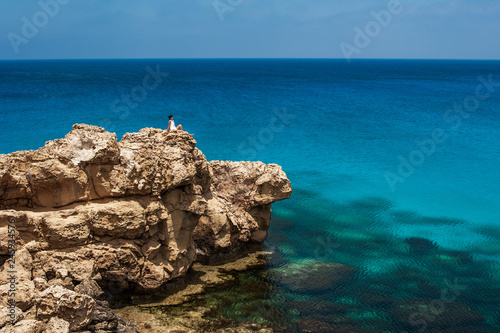 The girl on the cliff by the sea admiring nature. A man on the edge of a cliff by the sea. Tourist at the resort. The traveler looks at the sea. The rest of Europe by the sea. Beautiful seascapes