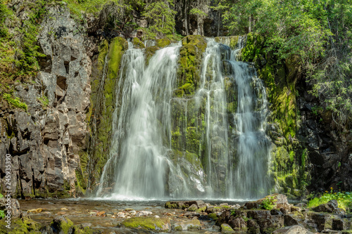 Fototapeta Naklejka Na Ścianę i Meble -  Waterfall flowing down a green moss covered rock wall