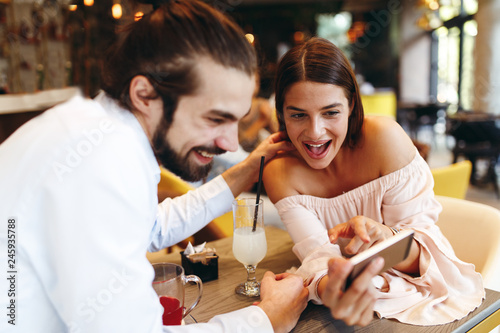 Young happy couple using smartphone in cafe
