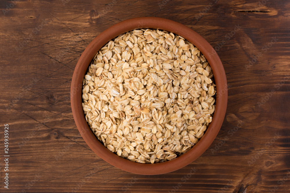 Rolled oats or oat flakes in bowl on wooden background. Healthy lifestyle, healthy eating concept. Top view Rolled oats or oat flakes in bowl on wooden background. Healthy lifestyle, healthy eating concept. Top view