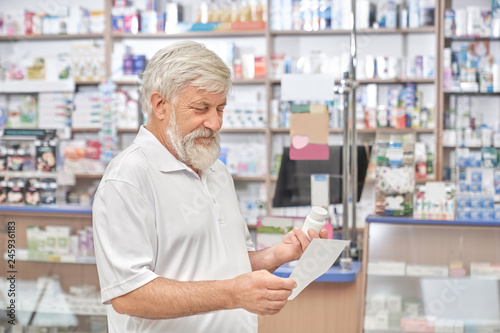 Pensioner looking at prescription in drugstore.