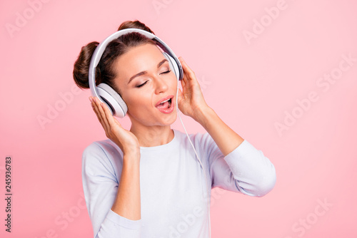 Close-up portrait of nice lovely sweet attractive cheerful peaceful girl wearing touching earphones singing melody isolated over pink pastel background