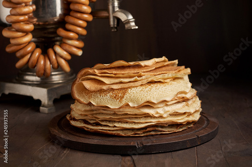 A traditional water boiler pot Russian Samovar with stack of thin pancakes blini