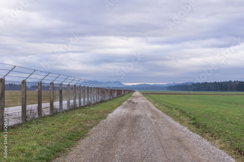 Long country road going straight on with fence on the right © 24K-Production