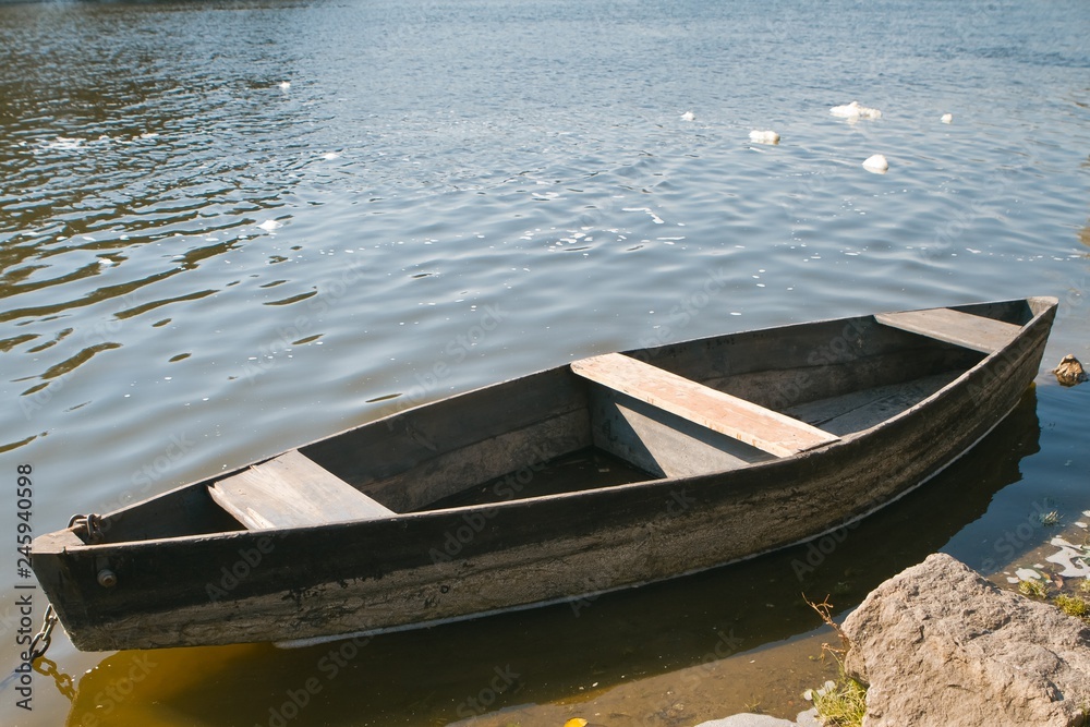 small old wooden fishing boat (punt) on the bank of a river