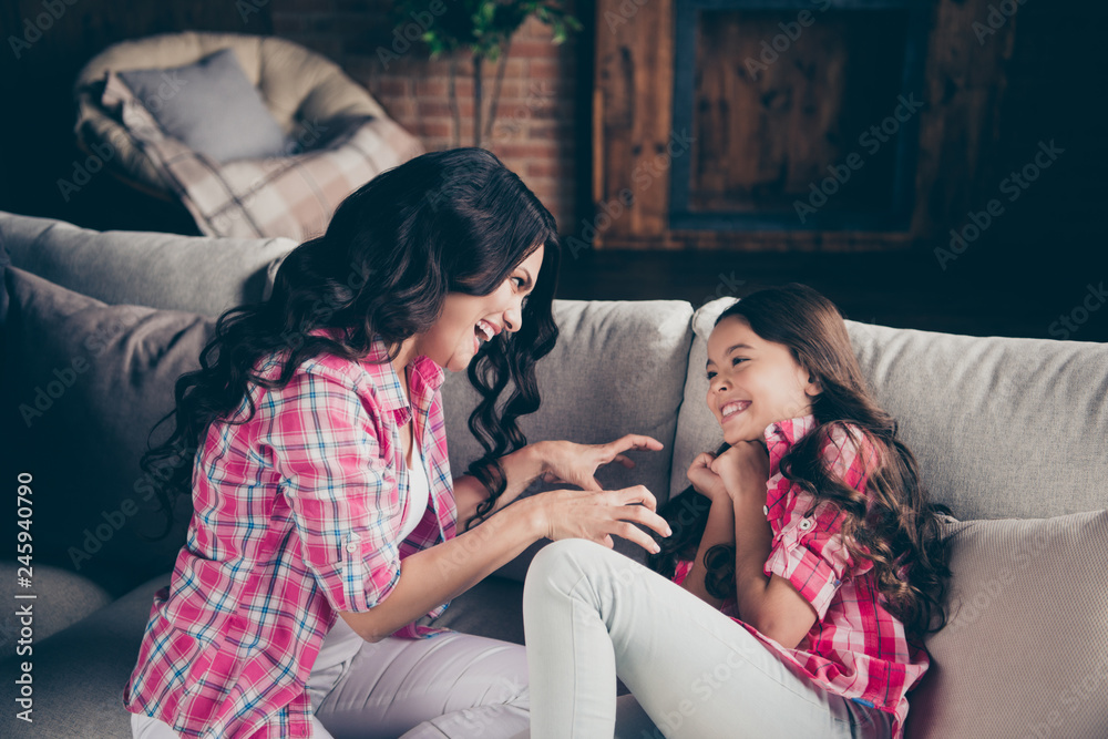 Close up photo two people mum little daughter overjoyed glad free time tickling animal grinning leisure rejoice wear pink plaid shirts jeans bright flat apartment room sit lying on cozy sofa divan