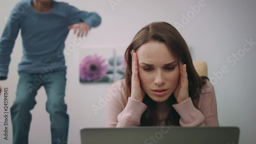 Stressed mother looking laptop at home. Woman calm down son