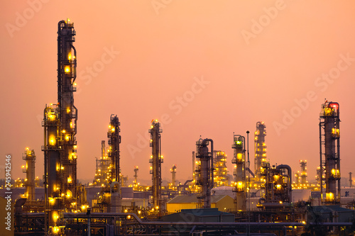 Glitter lighting of petroleum industrial with distillation tower on sunset sky background
