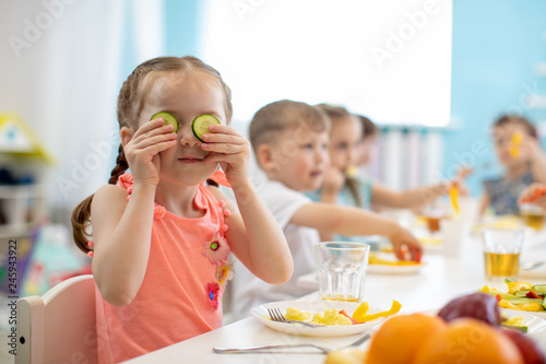 Funny kid eating healthy food in kindergarten or daycare