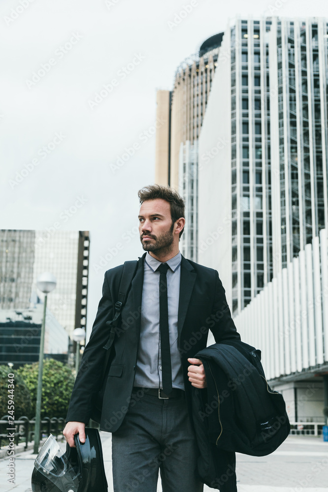 Elegant Businessman Walking in an Office Area with a Motorbike Helmet Elegant Businessman Walking in an Office Area with a Motorbike Helmet