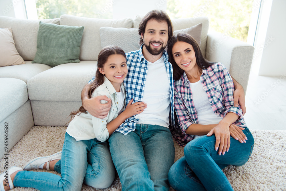 Nice cute lovely sweet tender attractive cheerful people mom dad sitting on floor carpet free time feelings friendship trust wearing jeans denim casual style in light white modern interior indoors