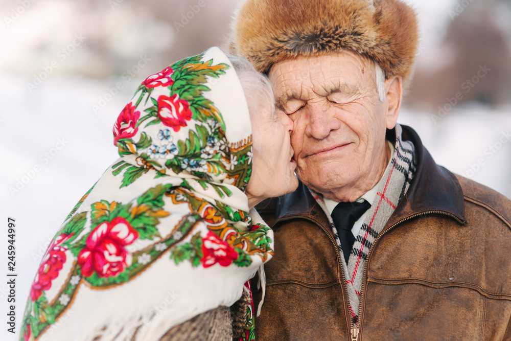 Portrait of happy senior couple. Elderly woman kiss her husband in weighty. old couple walkink in the park in winter time. Happy family. Gold wedding