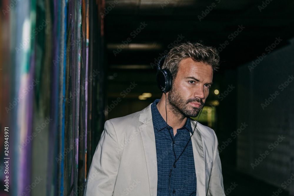 Elegant Young Man with Headphones Against a Graffiti Wall Elegant Young Man with Headphones Against a Graffiti Wall