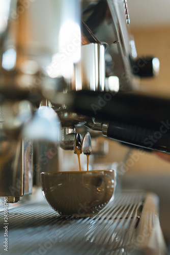 Side view of coffeee steaming from a coffee machine to a ceramic cup, fresh latte served in a cafe in the city center in the morning