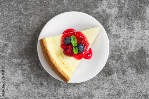 Canvas Print slice of cheesecake with fresh raspberries, blueberries, jam and mint on concrete background