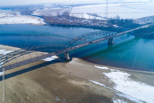 Gerola bridge in winter. Ancient iron bridge, built in 1913, on the river Po in the province of Pavia (Italy). River with little water due to drought. photo