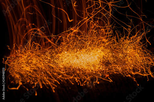 Burning fiery red hot sparks. Spark on bonfire in dark. Beautiful abstract background on the theme of fire.