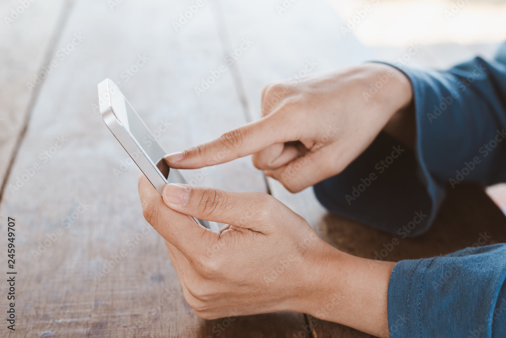 Hand holding smartphone on wooden table with copy space Hand holding smartphone on wooden table with copy space