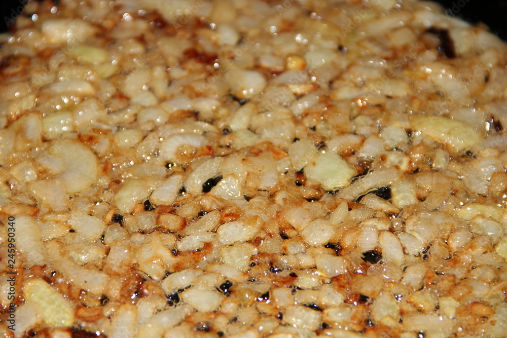 Onion slices closeup are roasted in griddle. Frying onions in pan Onion slices closeup are roasted in griddle. Frying onions in pan