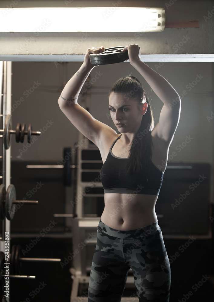 Fototapeta premium Beautiful young caucasian woman with black hair workout in fitness gym