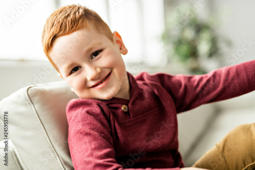 A Cute redhead boy sit on the sofa at home