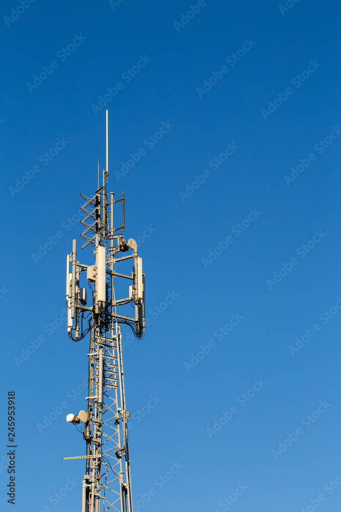 telecom tower lit by sun on a bright blue sky