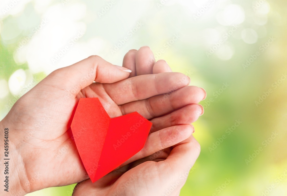 Hands of young woman holding red heart