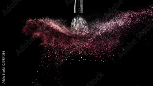 Cosmetic brush with red cosmetic powder spreading for makeup artist and graphic design in black background