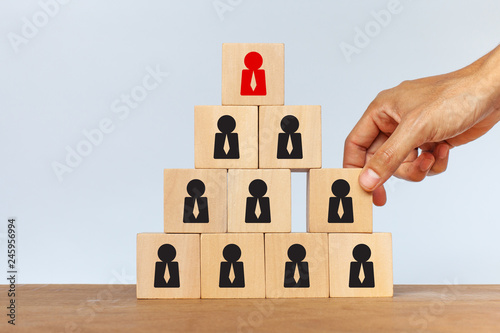 Hand arranging wooden cube stack as a pyramid on white background. Concept of human resources management and recruitment business