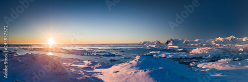 Sunset panoramic view of snow covered Antarctic land. Picturesque South Pole scenery. Beauty of the untouched nature. The wilderness landscape. Travel background. Holiday, hiking, sport, recreation
