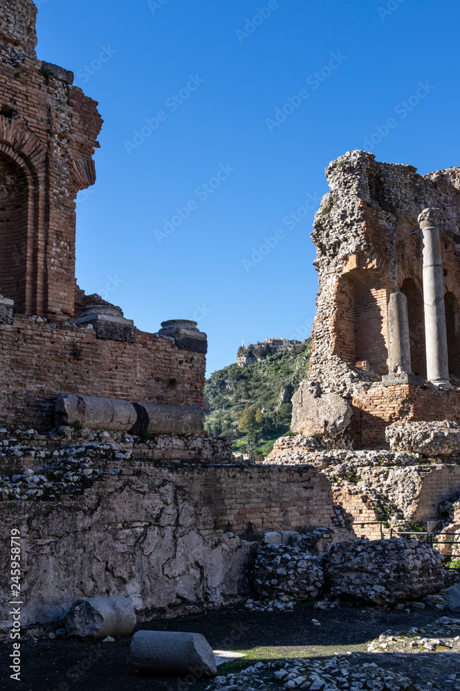 Ruins of ancient Greek theater in Taormina in Sicily. In background buildings on a top of hill