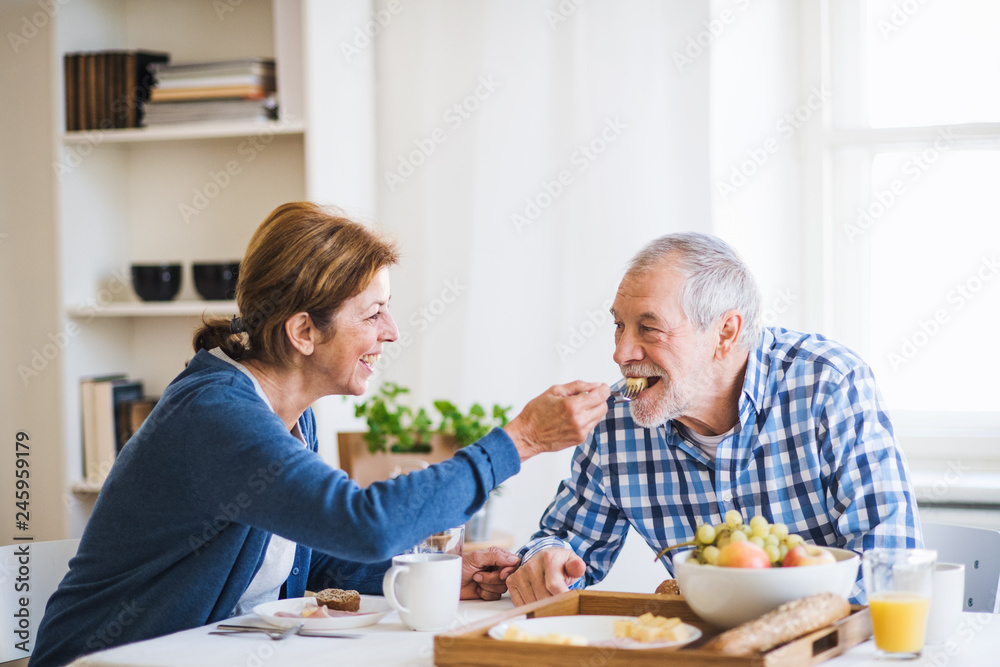 A senior couple sitting at the table at home, having breakfast. A senior couple sitting at the table at home, having breakfast.